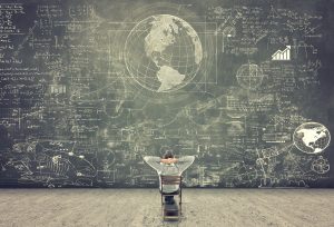 Professor sitting on a chair and studying math formulas on blackboard