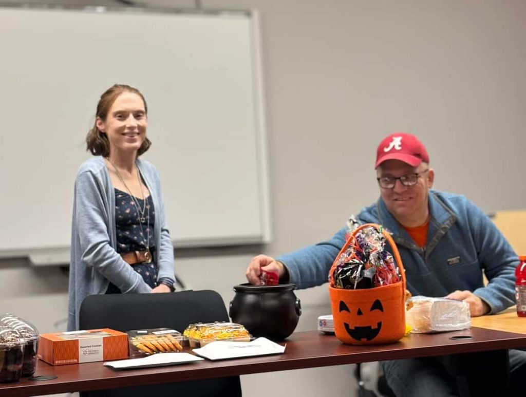 Jen and Dan photographed smiling in front of our Halloween party spread.